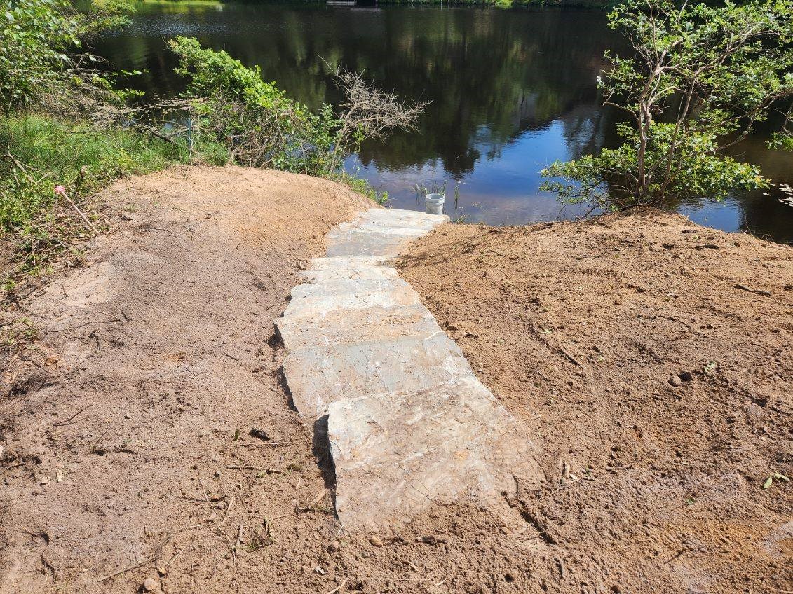 landscaping and hardscaping of stairs into a hillside down to a lake.